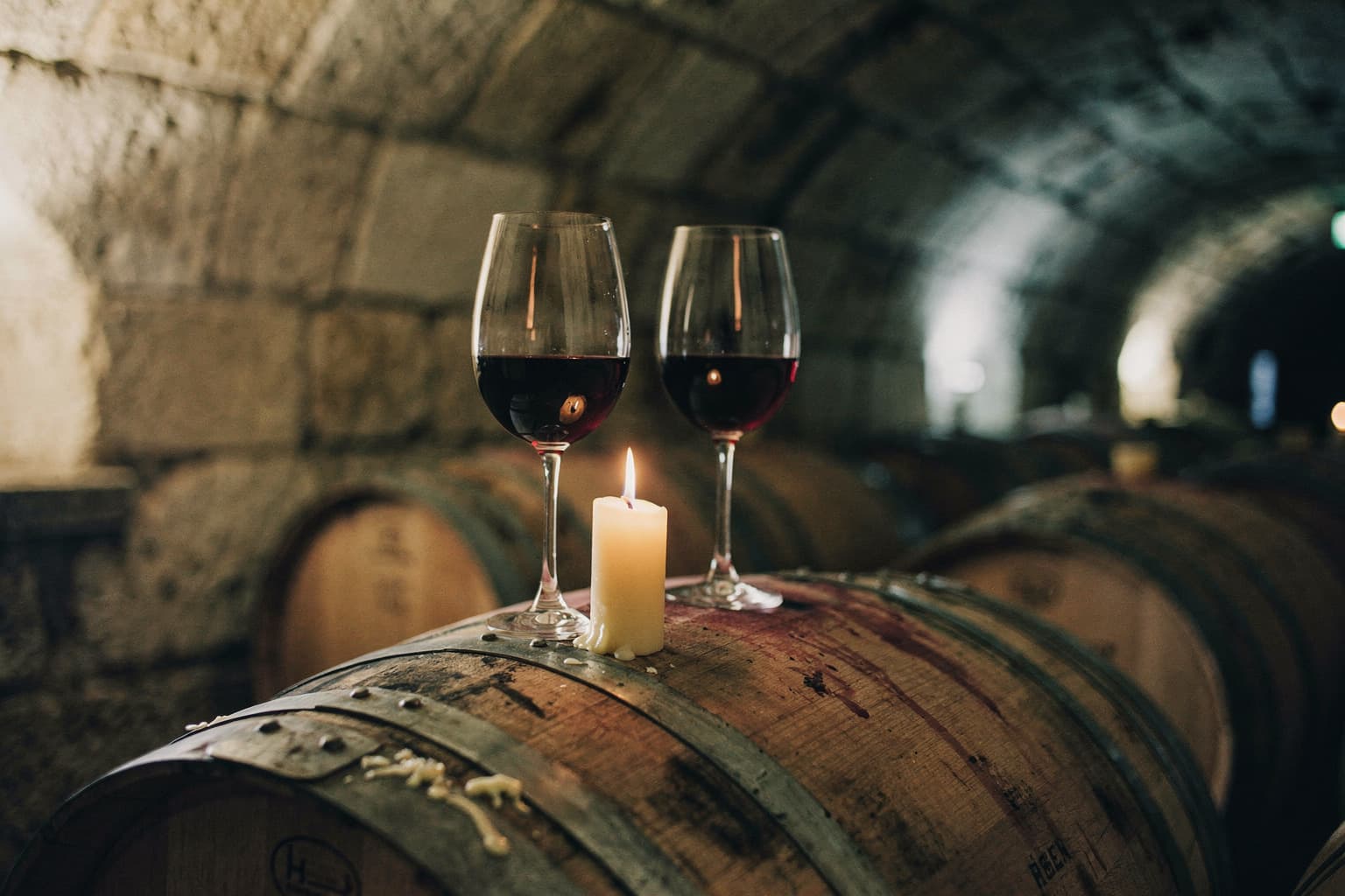 Two glasses and a candle on a barrel in the estate cellar